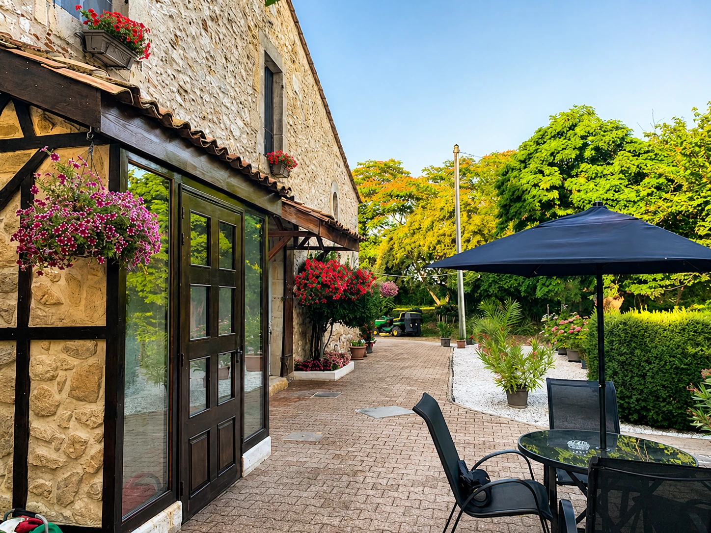 La Grâce patio walk with stone façade, flowers, paving and garden seating